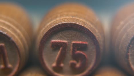 Cinematic-macro-smooth-shot-of-Bingo-wooden-barrels-in-a-row,-woody-figures,-old-numbers-vintage-board-game,-lucky-number-75,-slow-motion,-4K-commercial-gimbal-movement,-dreamy-lighting,-tilt-up