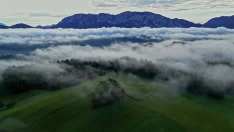 Aerial-view-of-foggy-fields-and-mountains,-on-the-countryside-of-gloomy-Austria