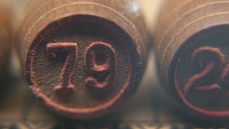 Cinematic-macro-smooth-shot-of-Bingo-wooden-barrels-in-a-row,-woody-figures,-old-numbers-vintage-board-game,-number-79,-slow-motion,-commercial-gimbal-movement,-dreamy-lighting,-pan-right