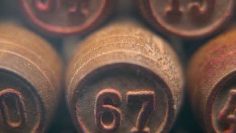 Cinematic-macro-smooth-shot-of-Bingo-wooden-barrels-in-a-row,-woody-figures,-old-numbers-vintage-board-game,-lucky-number-67,-slow-motion,-4K-commercial-gimbal-movement,-dreamy-lighting,-tilt-up