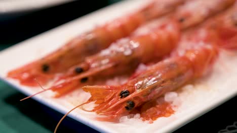 A-narrow-focus-view-of-homemade-oven-cooked-red-shrimps,-adorned-with-sea-salt,-elegantly-arranged-on-a-clean-white-platter