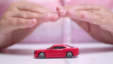 Close-up-shot-of-hands-hovering-over-a-small-toy-red-sportscar,-manifesting-a-desire-to-own-a-new-vehicle