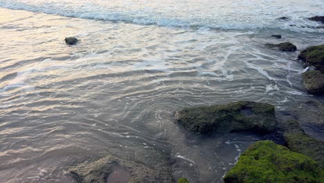 Anmutiges-Meerwasser-Ergießt-Sich-über-Sandige-Strandfelsen-In-Ruhiger-Küstenharmonie