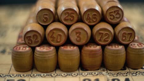Cinematic-close-up-smooth-forward-macro-shot-of-Bingo-wooden-barrels-in-a-row,-woody-figures,-old-numbers-background,-vintage-board-game,-slow-motion-120-fps-commercial-gimbal-video