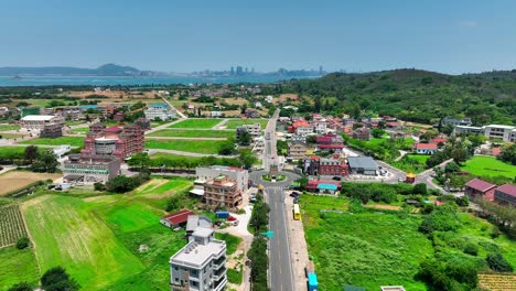 Aerial-flight-over-road-with-roundabout-and-buildings-on-Kinmen-Island-金門-Quemoy,-during-sunny-day-with-blue-sky,-Taiwan