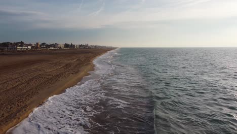 Castelldefels-Beach-in-Barcelona,-gentle-waves,-sandy-shore,-clear-sky,-serene-ambiance,-aerial-shot,-aerial-view