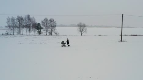 Single-mother-push-baby-carriage-on-snowy-road,-overcast-winter-weather