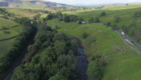 Drone-footage-flying-over-a-beautiful-shallow-tree-and-grass-lined-river-valley-in-sunny-rural-Yorkshire,-UK