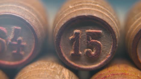 Cinematic-macro-smooth-shot-of-Bingo-wooden-barrels-in-a-row,-woody-figures,-old-numbers-vintage-board-game,-number-15,-slow-motion,-commercial-gimbal-movement,-pan-right