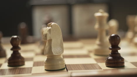 Frau-Spielt-Schach-In-Nahaufnahme,-Weibliche-Hand-Mit-Glänzendem-Nagellack-Bewegt-Den-Springer-Und-Macht-Schach