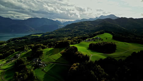 Aerial-drone-rotating-shot-over-mountain-range-covered-with-green-vegetation-beside-fjord-in-Norway-on-a-sunny-day