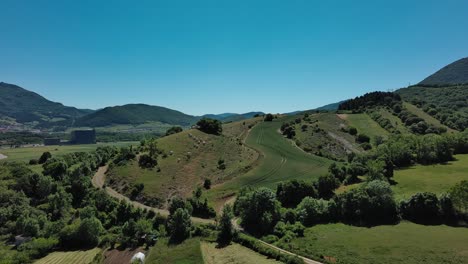 Green-hills-and-farmland-in-the-Basque-Country,-clear-blue-sky,-sunny-day,-aerial-view