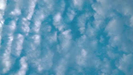 Ein-Filmischer-Zeitraffer-Von-Unten,-Surfende-Weiße-Wolken,-Blauer-Himmel,-Tageslichtsonne,-Statisches-4K-Video