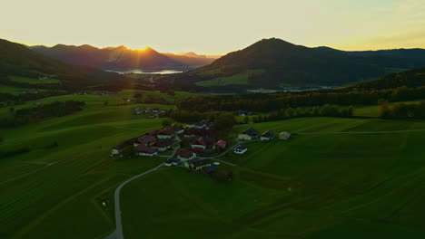 Luftdrohnenschwenkaufnahme-Von-Links-Nach-Rechts-über-Einem-Kleinen-Dorf,-Umgeben-Von-Einer-Bergkette-In-Norwegen,-Mit-Sonnenaufgang-Im-Hintergrund