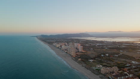 Aerial-view-of-long-sandy-beach-with-buildings-on-the-Cullera-coast-during-sunset-light