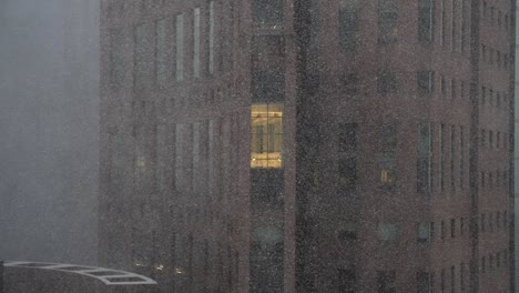 Tight-view-of-old-building-exterior-with-white-out-snowy-blizzard-blowing-in-slow-motion-from-the-side-with-single-light-on