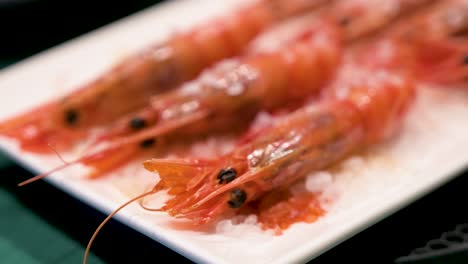Narrow-view-of-an-exquisite-dish-featuring-oven-cooked-seafood-red-shrimps,-presented-on-a-white-platter,-accentuated-by-the-delicate-addition-of-sea-salt