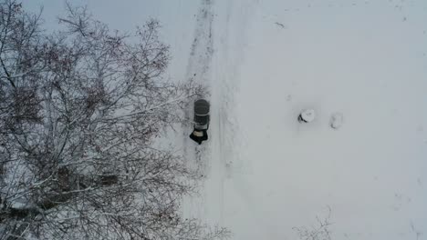 Aerial-top-down-view-of-mother-push-baby-stroller-on-snowy-countryside-road