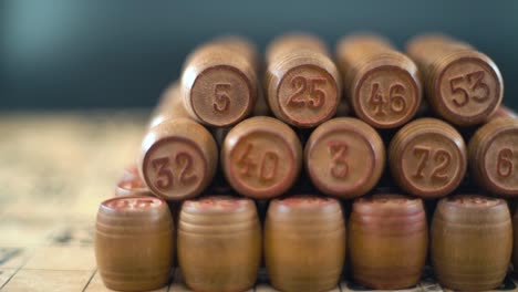 Cinematic-creative-smooth-dreamy-shot-of-Bingo-wooden-barrels-in-a-row,-woody-figures,-old-numbers-background,-vintage-board-game,-slow-motion-120-fps-commercial-gimbal-video,-crane-movement