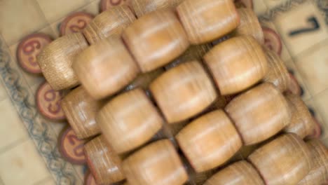 Cinematic-creative-smooth-dreamy-rotating-macro-shot-from-above-of-Bingo-wooden-barrels-in-a-row,-woody-figures,-old-numbers-background,-vintage-board-game,-slow-motion-120-fps-commercial-gimbal-video