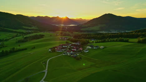 Aerial-drone-rotating-shot-over-a-small-village-in-a-valley-with-mountain-range-surrounding-on-all-sides-in-Norway-at-sunrise