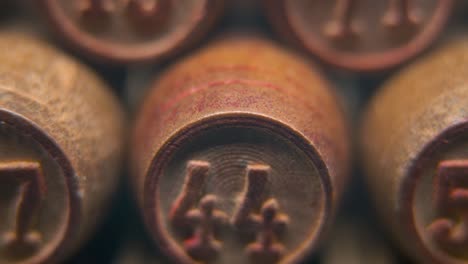 Cinematic-macro-smooth-shot-of-Bingo-wooden-barrels-in-a-row,-woody-figures,-old-numbers-vintage-board-game,-lucky-number-44,-slow-motion,-4K-commercial-gimbal-movement,-dreamy-lighting,-tilt-up