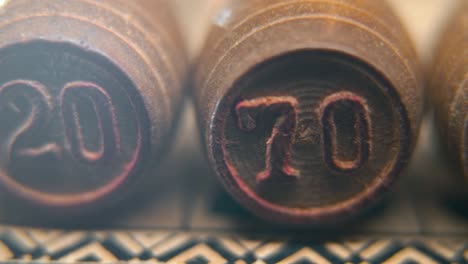 Cinematic-macro-smooth-shot-of-Bingo-wooden-barrels-in-a-row,-woody-figures,-old-numbers-vintage-board-game,-number-70,-slow-motion,-commercial-gimbal-movement,-dreamy-lighting-pan-right
