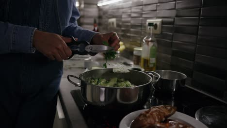 Girl-cutting-up-parsley-in-the-kitchen,-cooking-dinner-at-home-in-the-evening,-healthy-eating,-vegan-diet,-vegetarian-meal,-potatoes,-electric-stove,-meal-prepping,-olive-oil,-close-up-cinematic-shot