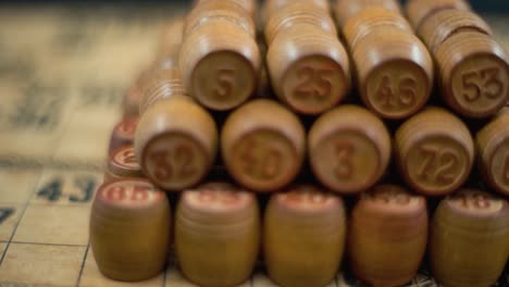 Cinematic-fantasy-smooth-dreamy-rotating-forward-macro-shot-of-Bingo-wooden-barrels-in-a-row,-woody-figures,-old-numbers-background,-vintage-board-game,-slow-motion-120-fps-commercial-gimbal-video