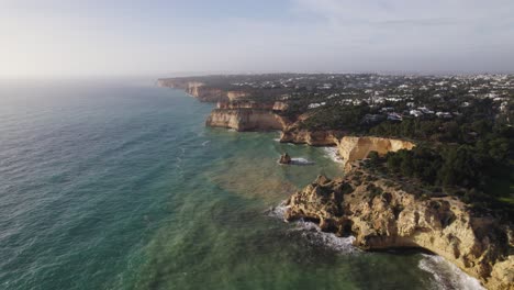 Stunning-rugged-cliffs-on-the-coast-of-town-Carvoeiro-in-Portugal,-aerial-flyover