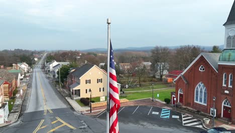 Aerial-shot-of-an-American-flag-outside-a-brick-church