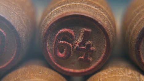 Cinematic-macro-smooth-shot-of-Bingo-wooden-barrels-in-a-row,-woody-figures,-old-numbers-vintage-board-game,-lucky-number-64,-slow-motion,-4K-commercial-gimbal-movement,-dreamy-lighting,-tilt-up