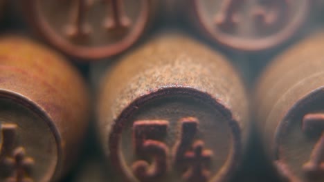 Cinematic-macro-smooth-shot-of-Bingo-wooden-barrels-in-a-row,-woody-figures,-old-numbers-vintage-board-game,-lucky-number-54,-slow-motion,-4K-commercial-gimbal-movement,-dreamy-lighting,-tilt-up