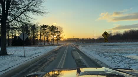 Country-road-sunset-during-winter,-cold-snow-covered-landscape-during-sunset