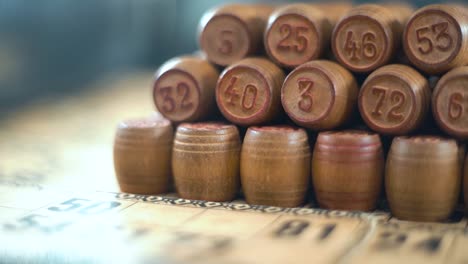 Amazing-creative-smooth-dreamy-macro-shot-of-Bingo-wooden-barrels-in-a-row,-woody-figures,-old-numbers-background,-vintage-board-game,-slow-motion-120-fps-commercial-gimbal-video,-crane-movement