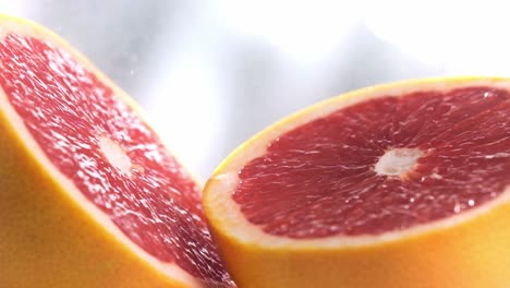 Water-spraying-particles-falling-on-Sliced-Grapefruit-surface-in-Slow-motion,-Extreme-close-up