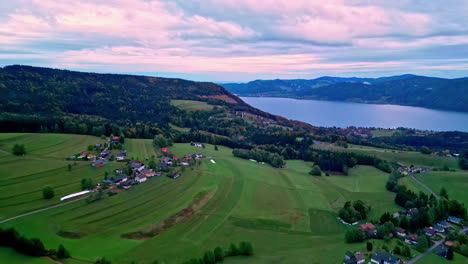 Aerial-drone-forward-moving-shot-over-village-houses-beside-a-fjord-surrounded-by-mountain-range-in-Norway-on-a-cloudy-day