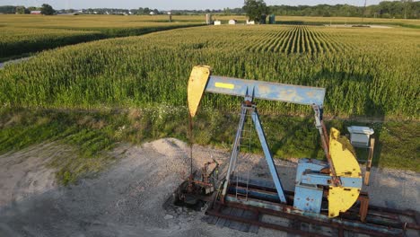 Pumpjack-pumping-oil-surrounded-with-agriculture-field,-aerial-view