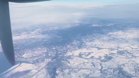 A-4k-flight-over-snow-in-North-West-England-over-Ellesmere-Port-Liverpool-in-a-turboprop-airplane-with-propeller-blur