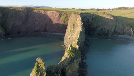 drone-flying-over-sea-cliff-leading-to-two-sheltered-beaches-at-golden-hour-Copper-Coast-Waterford-Ireland