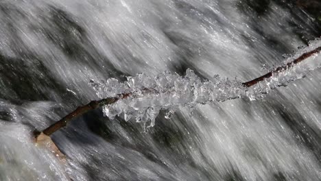 Ein-Eisbedeckter-Ast-An-Einem-Kleinen-Wasserfall