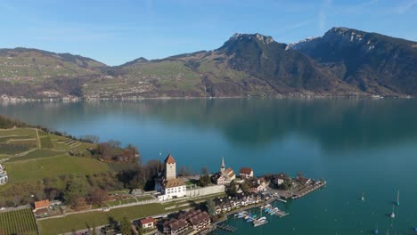 Spiez-in-Switzerland-showcasing-the-serene-Lake-Thun-against-the-majestic-Swiss-Alps,-vibrant-landscape,-aerial-view