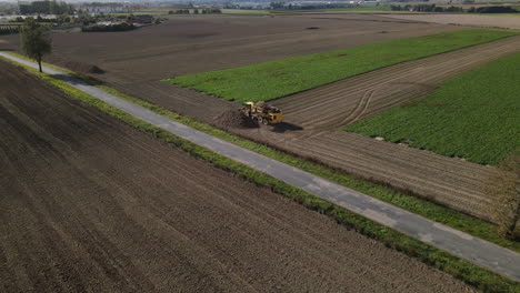 Harvester-turning-on-field-edge,-dumping-collected-beets---aerial-shot