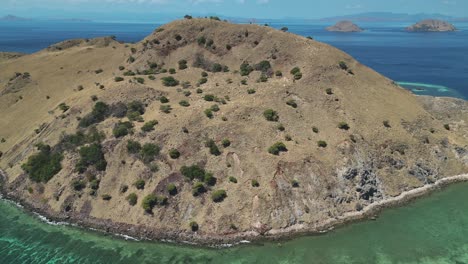 Drone-view-revealing-a-dry-barren-island-surrounded-by-a-rich-coral-reef