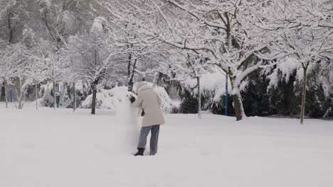 Mujer-Haciendo-Muñeco-De-Nieve-En-Un-Parque-Público-En-Un-Día-Nevado
