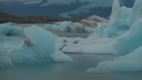 Gletscher-Schwimmen-In-Der-Gletscherlagune,-Island,-Mit-über-Ihnen-Fliegenden-Möwen,-Vor-Dem-Hintergrund-Des-Blauen-Wassers,-Das-Sich-In-Richtung-Diamond-Beach-Bewegt