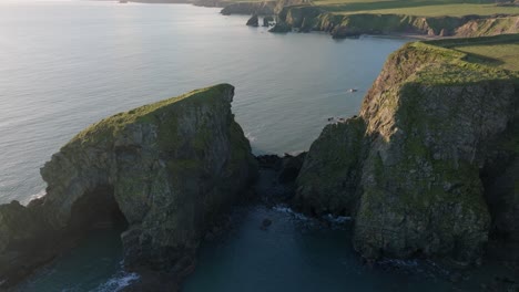 Drohnenüberflug-über-Meeresstapel-Zur-Bucht-Mit-Fischerboot-Bei-Der-Arbeit,-Atemberaubende-Schönheit-Der-Kupferküste-Irlands