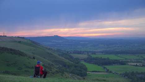 Man-on-a-camping-chair,-watching-the-sunset-in-a-picturesque-valley-in-England