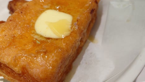Nahaufnahme-Eines-Goldenen-French-Toasts-Mit-Geschmolzener-Butter-Darauf,-Der-Auf-Einem-Teller-Aufbewahrt-Wird