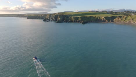 drone-cinematic-copy-space-fishing-boat-travelling-up-coast-at-Ballydwane-Bay-Copper-Coast-Ireland-late-afternoon-at-golden-hour